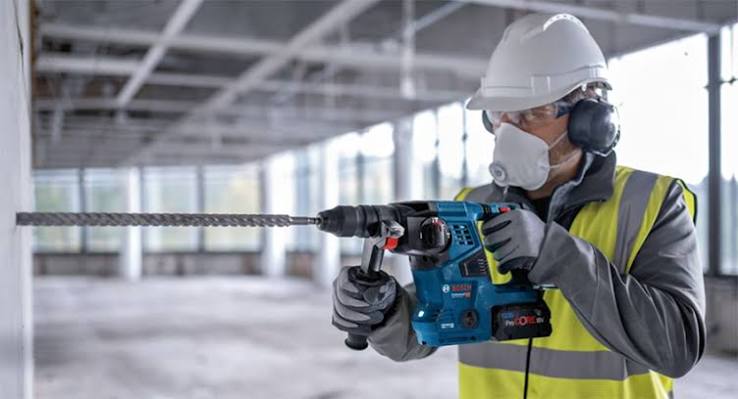 Hantverkare som borrar i betongvägg med en batteridriven borrhammare.