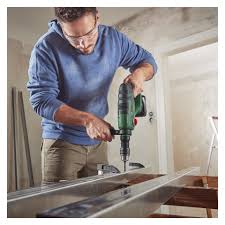 Hemmafixare som borrar i vägg med borrhammare under en renovering.