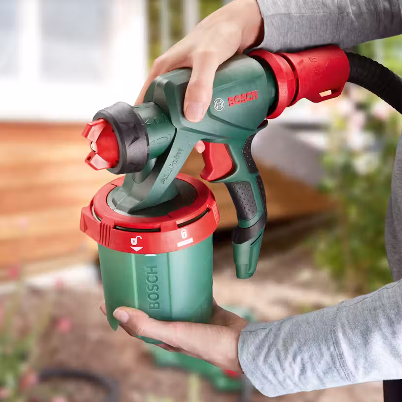 Bosch färgspruta med slang och färgbehållare på en arbetsbänk.